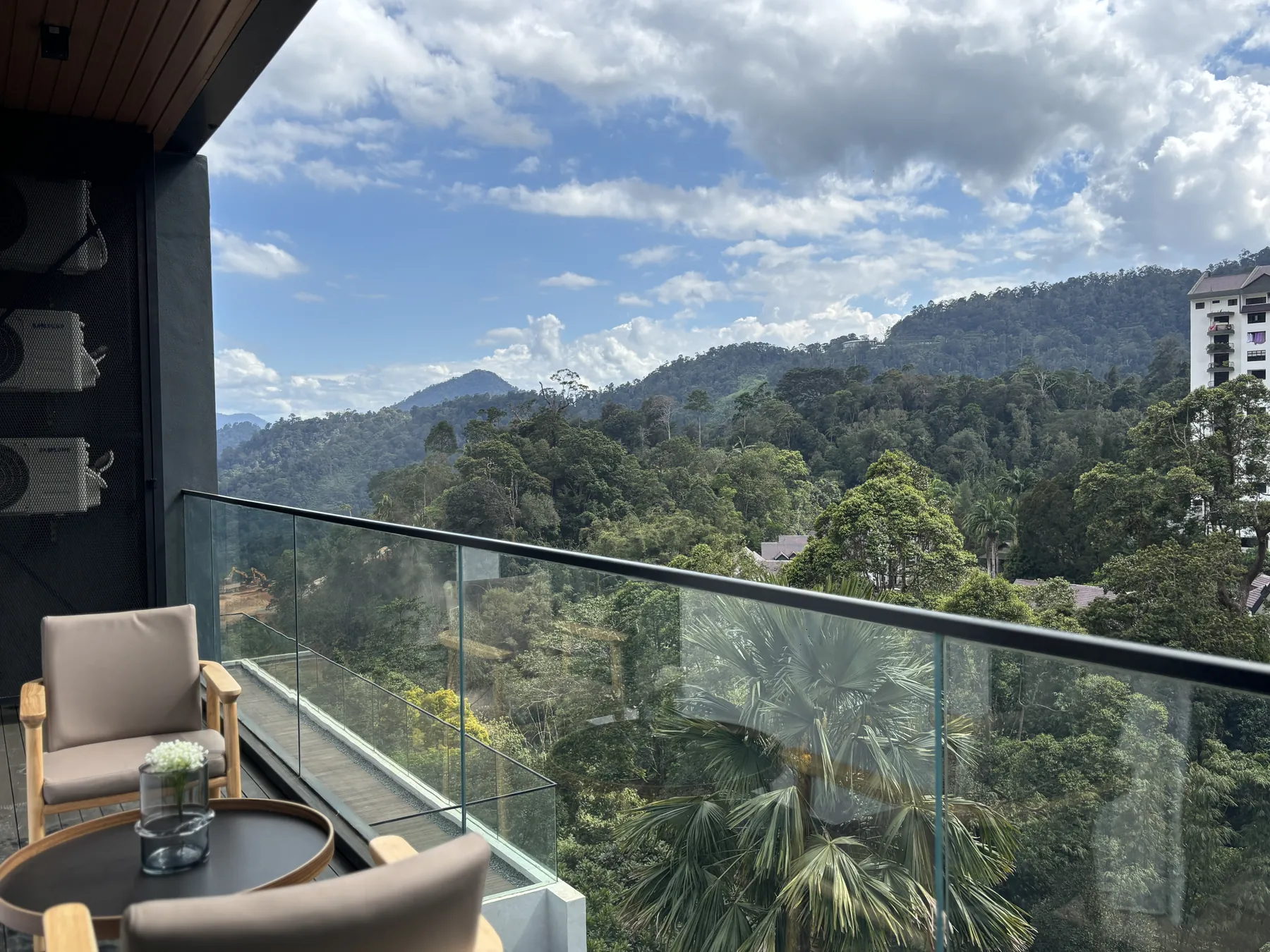 Private balcony framed in glass, looking out over the forested hills